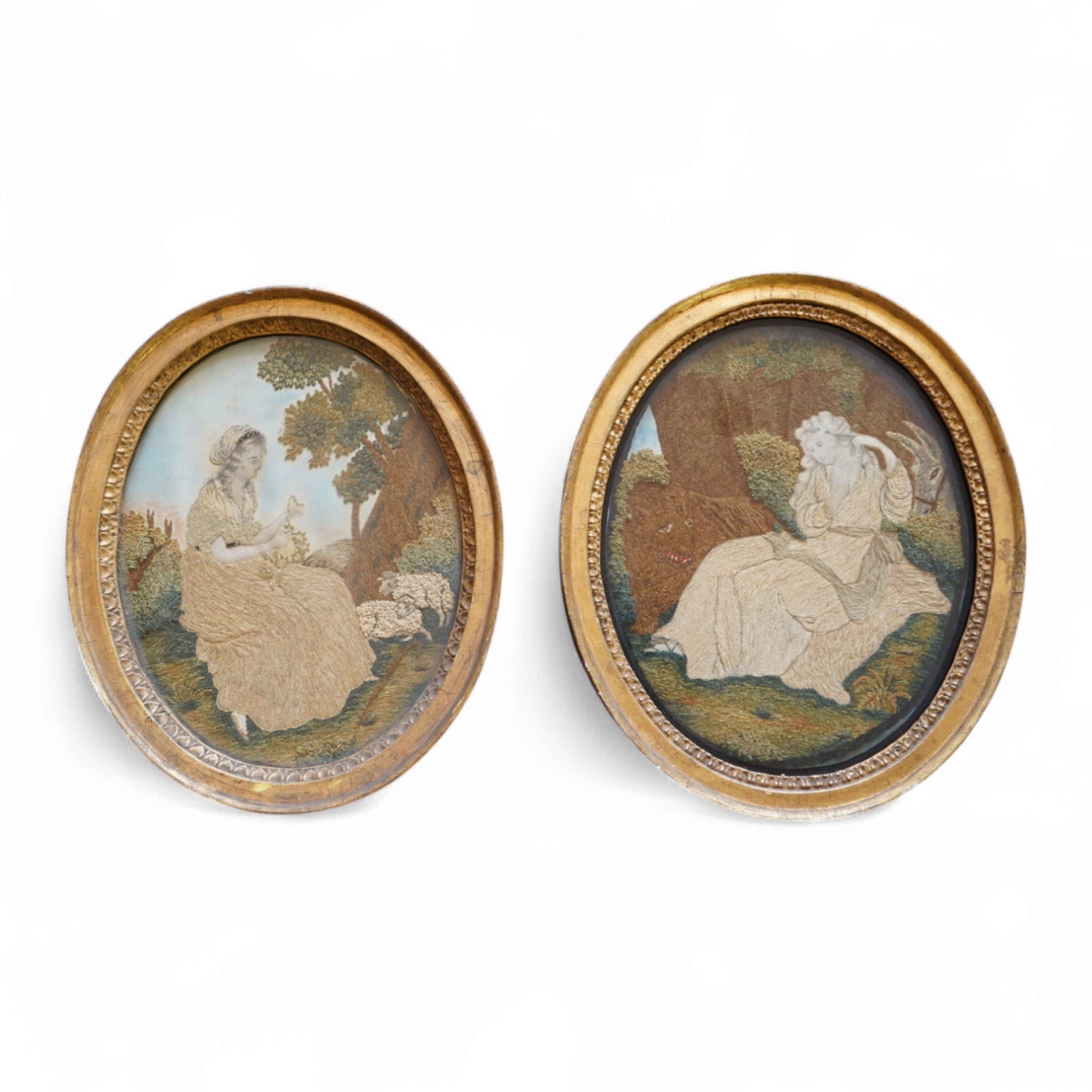 A pair of unusual early 19th century oval silk Chenille embroideries, one depicting a seated lady surrounded by a lion and donkey, the other depicting a seated shepherdess under tree with two sheep. Both have water colou